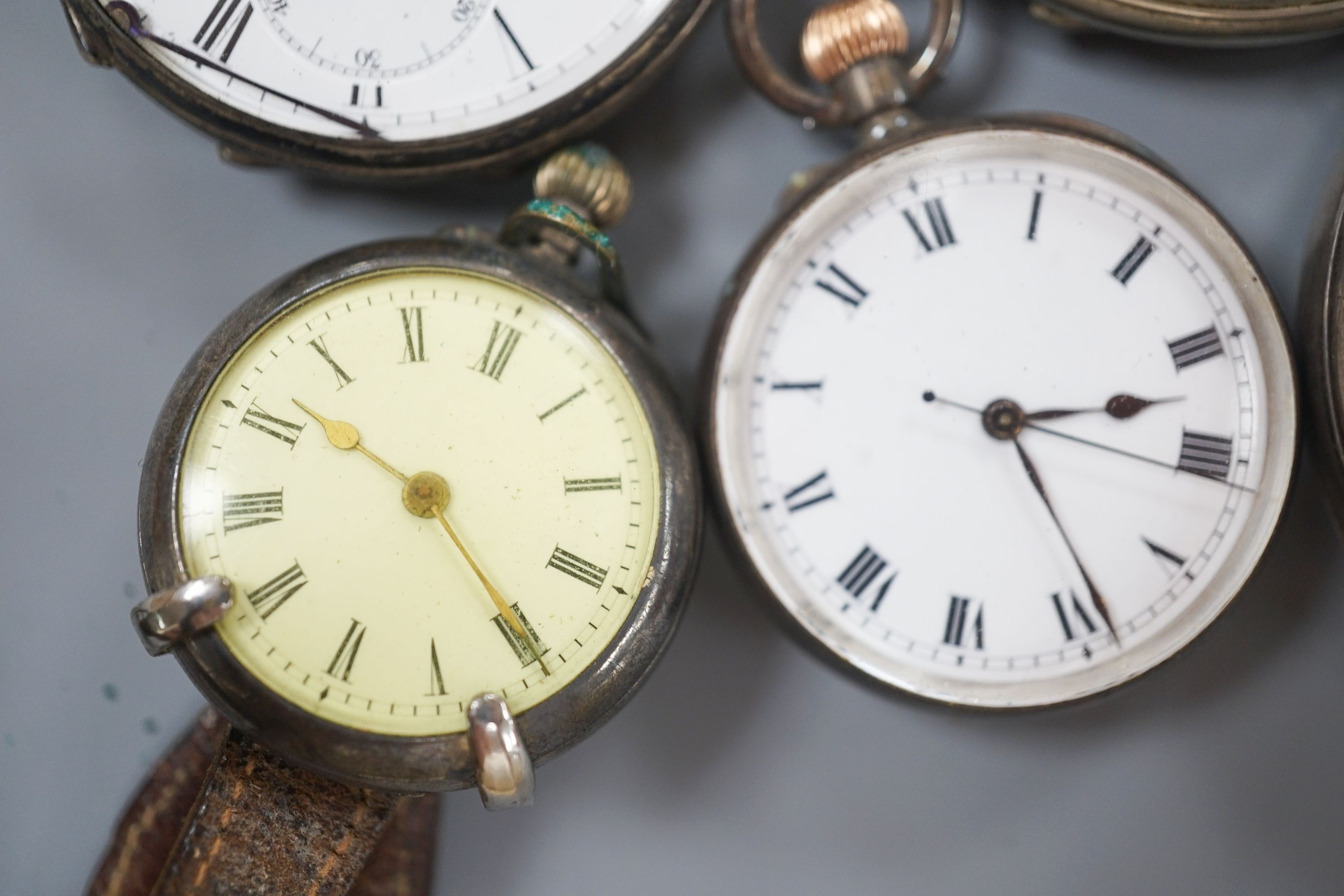 An early 20th century silver open face pocket watch, two white metal fob watches, a white metal wrist watch and one other pocket watch.